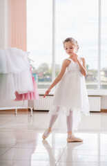 Wall Mural - Cute little ballerina in white dress and pointe shoes dreams about ballet dances.