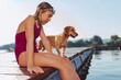 Girl sitting on the river dock with her dog