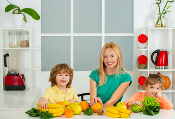 Wall Mural - Young mother and her two children eating fruits and drinking smoothie, mothers day concept, Healthy food at home.