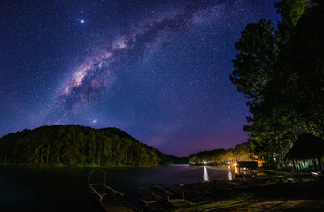 Wall Mural - milky way galaxy on mountain reservoirs and pine forests long exposure photograph, with grain.image 