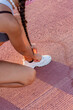 © victor rangel - Mujer joven deportista con mascarilla atándose los cordones de los zapatos en la pista de atletismo.