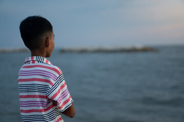 ฺAbstract and blur of asian boy stands back to look at the sea in the evening.