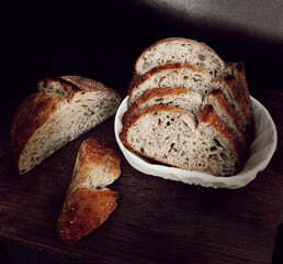 High hydration bread, long and slow cold fermentation, made from wheat flour sourdough just out of the oven on wooden table, banneton and black background