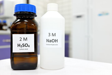 Wall Mural - Selective focus of sodium hydroxide base and sulfuric acid solution in brown glass and plastic bottle inside a chemistry laboratory. White background with copy space.