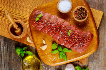 Wall Mural - Raw beef steaks with black peppercorn and salt on wooden board.