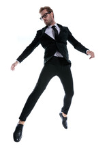 dramatic cool young man in black suit jumping in the air