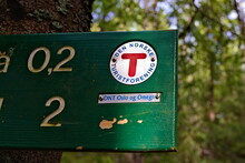 Logo Of The Norwegian Hiking Association On A Signpost In The Woods. 