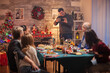 © DC Studio - Smiling man taking group photos of his family at christmas celebration.