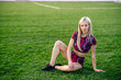 © Maria - Beautiful young blonde woman in sportswear sits on the grass in the stadium before training