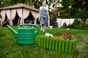 Watering can in the garden, gardener on background