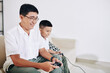 © DragonImages - Mature Vietnamese man enjoying playing videogame with his preteen son at home