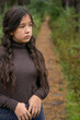 © dinastiya - A young girl  stands on a forest path against the background of a beautiful forest corridor with a well-trodden path