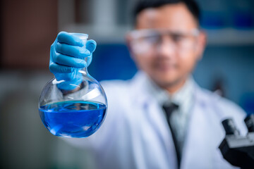 Wall Mural - the special young male scientis or reseacher looking the chemical solution through the test tube for