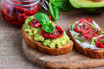 Sandwich with sun-dried tomatoes, avocado, basil, curd cheese on croutons. Vegetarian breakfast or snack