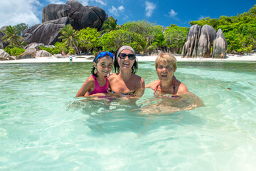 Young girl with mother and grandmother relaxing in the water, tropical island vacation