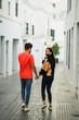 © MiguelAngelJunquera - Pareja joven cogida de la manos caminando por pueblo blanco