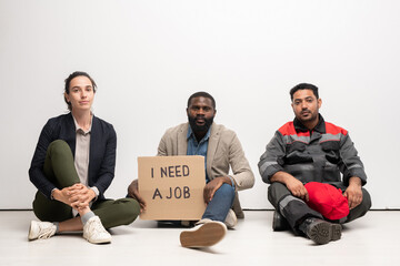 Poster - Group of young intercultural jobless people in casualwear sitting on the floor