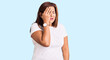 Middle age latin woman wearing casual white tshirt yawning tired covering half face, eye and mouth with hand. face hurts in pain.