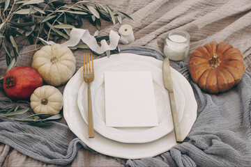 Wall Mural - Autumn table setting with golden cutlery, olive branches and porcelain plate. Pumpkins and pomegranate fruit. Blank menu card mockup. Fall, Thanksgiving and Rosh Hashanah celebration concept.
