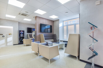 Trendy and modern office in white colors with the waiting area for clients .The coffee wending machine next to the coffee point.