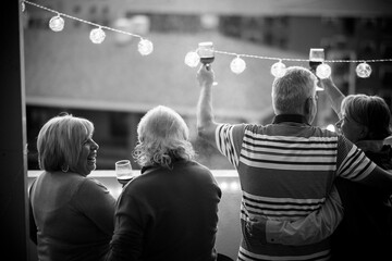 Wall Mural - Group of cheerful and happy senior friends people clinking and enjoying together the dinner outdoor in terrace at home with city view - people together celebrating  - retired life concept