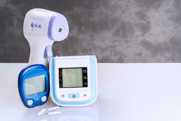 Remote thermometer, blood glucose meter and wrist blood pressure monitor on table with copy space. Home medical devices