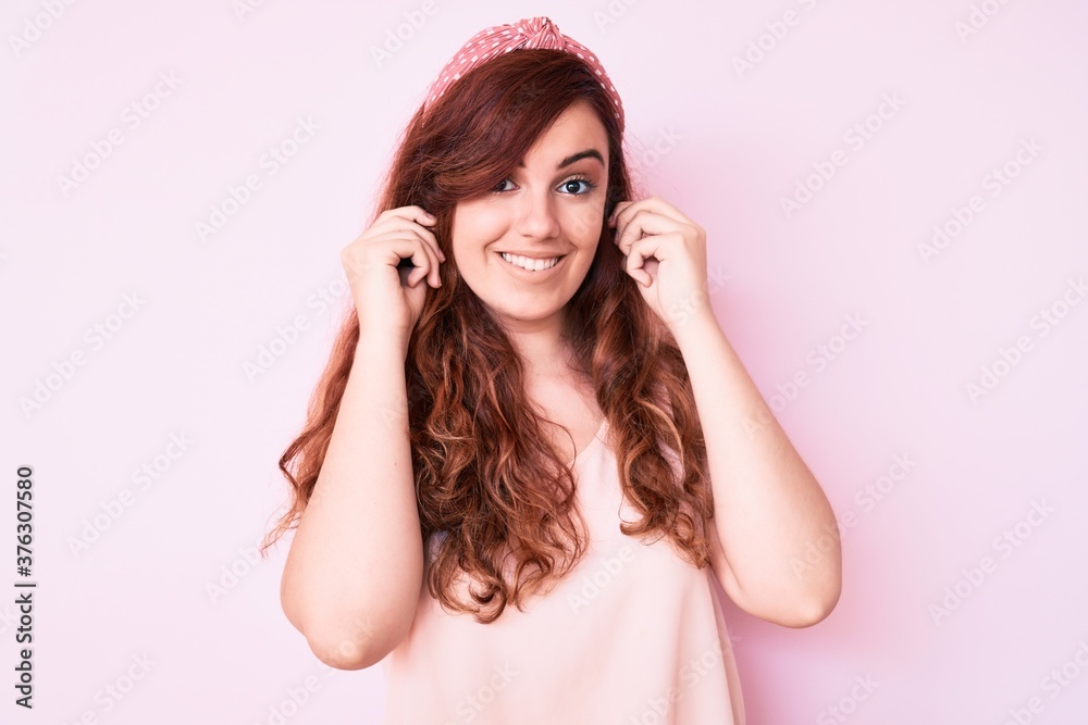 Young beautiful woman wearing casual clothes smiling pulling ears with fingers, funny gesture. audition problem