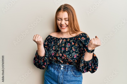 Cuadros en Lienzo Young beautiful redhead woman wearing casual floral clothes celebrating surprise