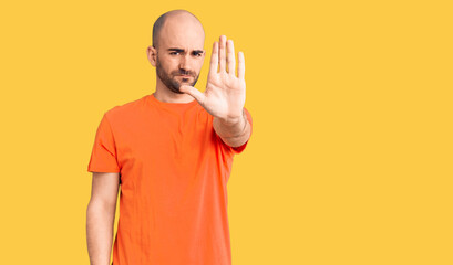 Young handsome man wering casual t shirt doing stop sing with palm of the hand. warning expression with negative and serious gesture on the face.