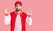 © Krakenimages.com - Young handsome man with beard wearing baseball jacket and cap relax and smiling with eyes closed doing meditation gesture with fingers. yoga concept.