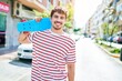 © Krakenimages.com - Young caucasian skater man smiling happy holding skate walking at street of city.