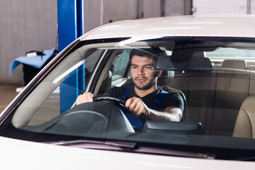 Repairman sitting in a car in the front seat and holds the wheel