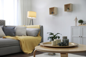 Wall Mural - Wooden table with candles and tray near sofa in living room. Interior design