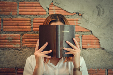 Wall Mural - A young Christian woman closes her scriptures reading and studying in her room on Sunday.