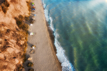 Wall Mural - Aerial coast with tents as camping background. Summer seascape with sand beach and turquoise sea view. Hiking and camping holidays concept Travel