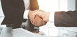 © Iryna - Unknown diverse business people are shaking hands finishing contract signing in sunny office, close-up. Business handshake concept
