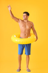 Wall Mural - Happy young man with inflatable ring on color background