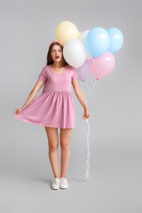 Sticker - Surprised young woman with balloons on grey background