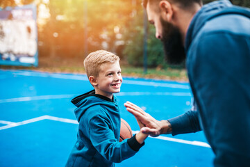 Wall Mural - Father and his son enjoying together on basketball court.