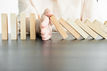 Hands of businesswoman stop block a wood game, gambling placing a wooden block. Concept Risk of management and strategy plan, protect business to success