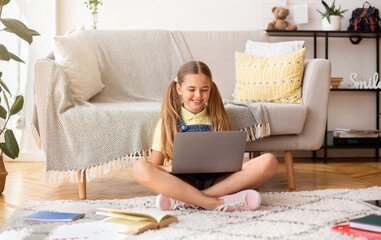 Wall Mural - Girl sitting on floor carpet and using laptop computer