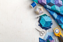 Fragment Of Tumbling Blocks Quilt, Accessories For Quilting On A White Surface. Space For Text.