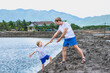 © NOVOZHILOV ANDREI - Dad helps son go down to lake water, explains safety rules. Family together walk play. Home natural child education, fathers day, fatherly responsibilities, influence on formation of son worldview