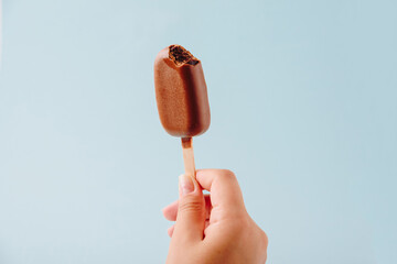 Chocolate cake in the form of ice cream on a stick on a white plate and a colored background