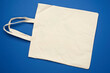 empty beige textile bag on blue background, rejection of plastic bags