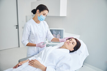 Wall Mural - Qualified dermatologist in sterile gloves examining the patient