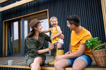 Young family with small daughter outdoors, weekend away in container house in countryside.