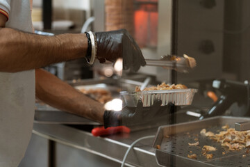 Wall Mural - Close-up of a chief with latex gloves cutting and preparing chicken and beef doner kebab.