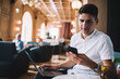 © BullRun - Young man chatting on smartphone and using laptop in restaurant