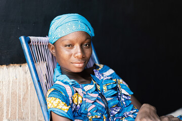 Portrait of Adolescent Young College Girl Sitting in Chair with Blue Typical African Wax Dress